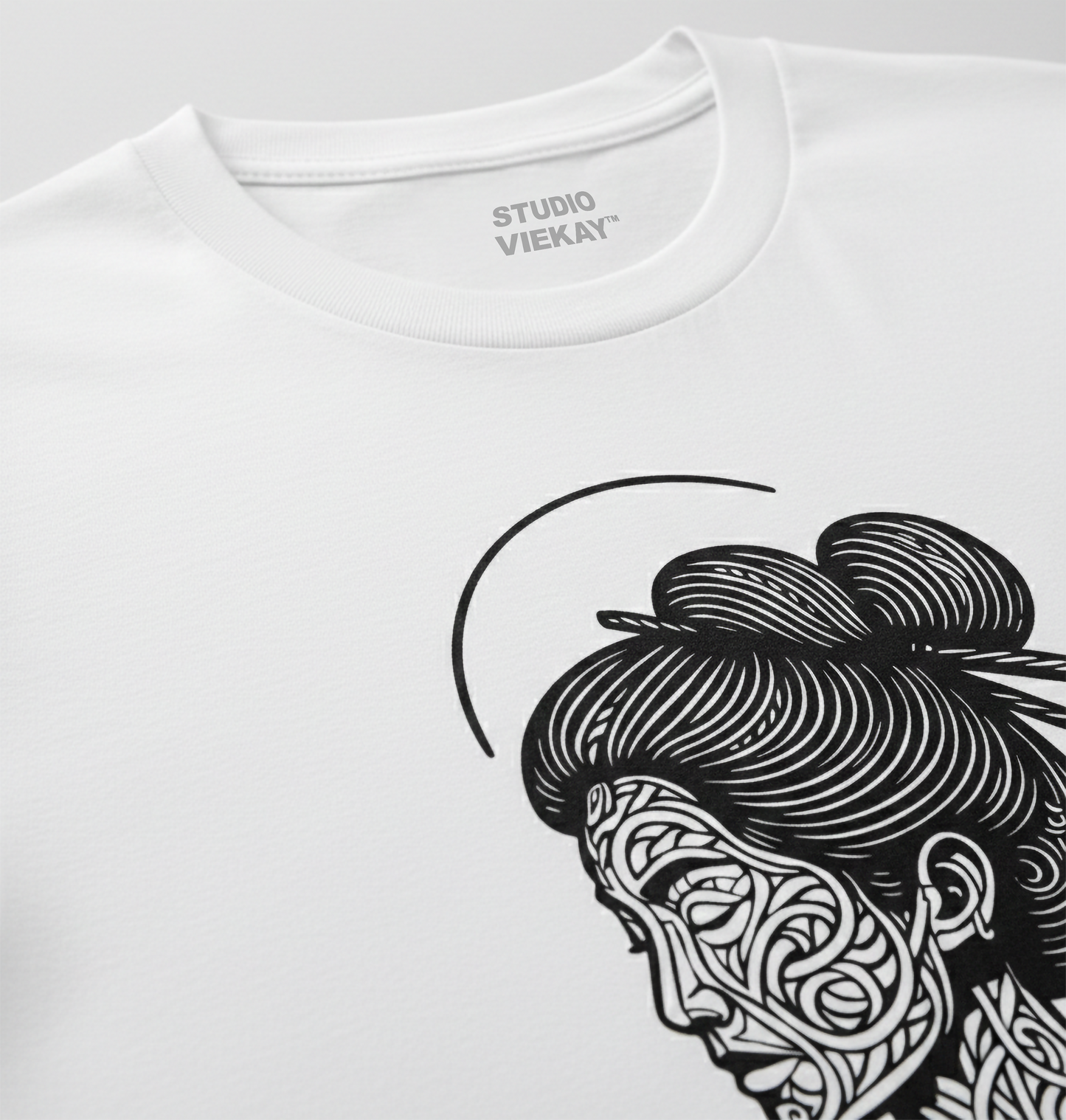 Close up of a white t-shirt with black and white graphic design of a Geisha face on a gray background
