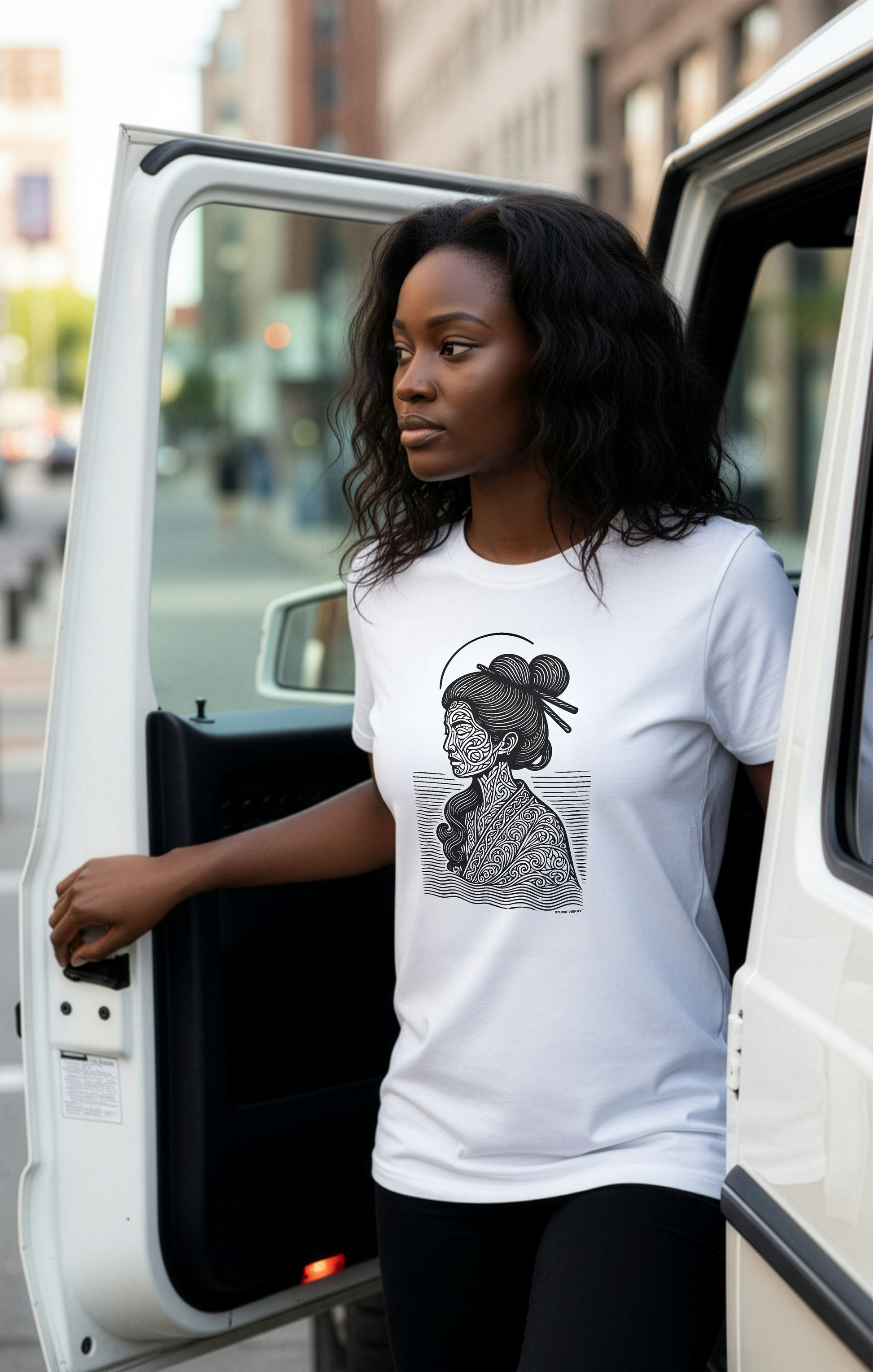 A model wearing a white t-shirt with a Studio VieKay design, standing next to a white G-wagon.