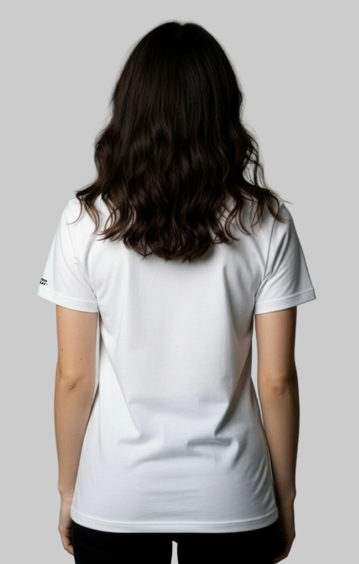 The back view of a female model wearing a white Studio Viekay t-shirt against a gray background