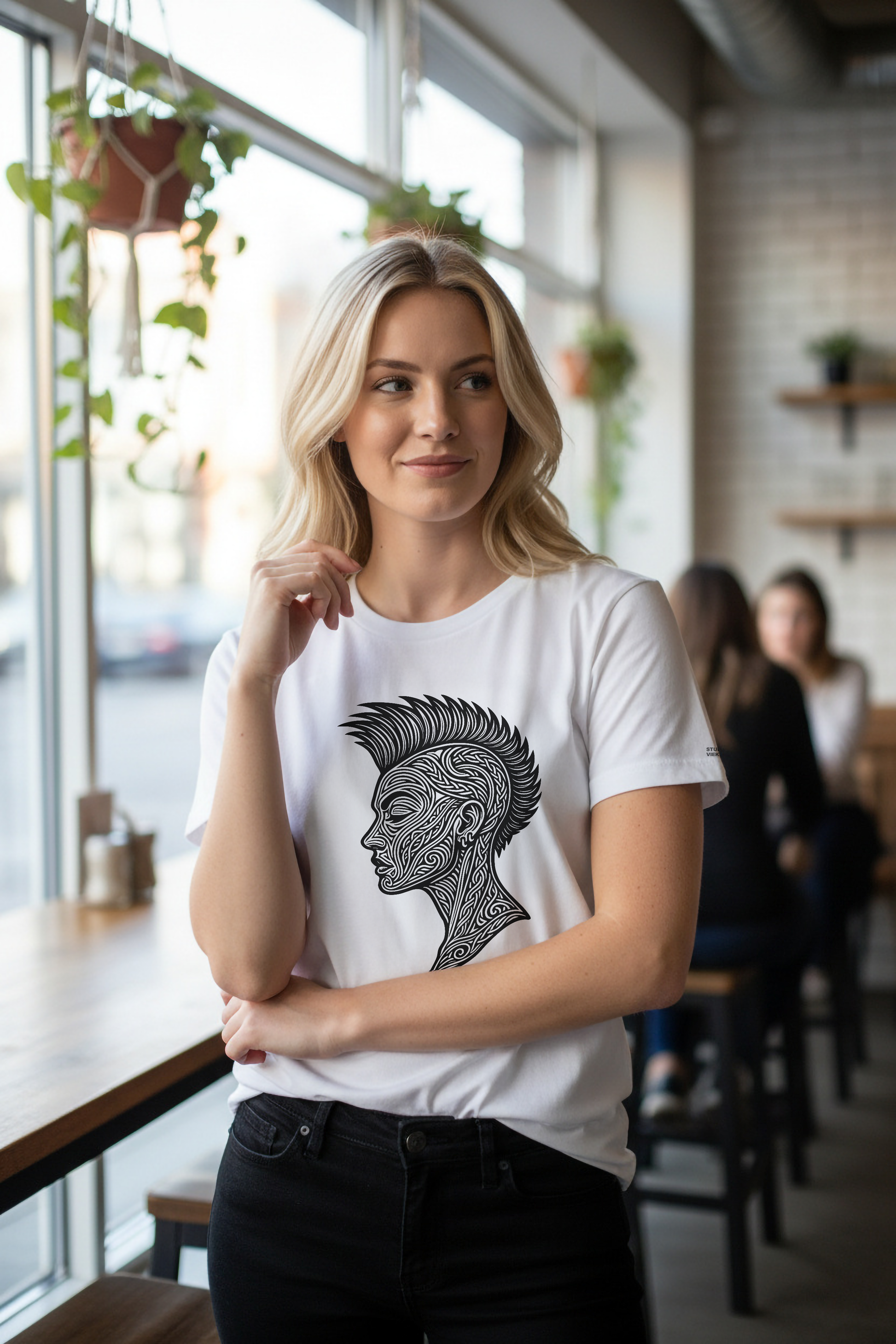 Model wearing a white t-shirt with a black graphic design in a cafe setting