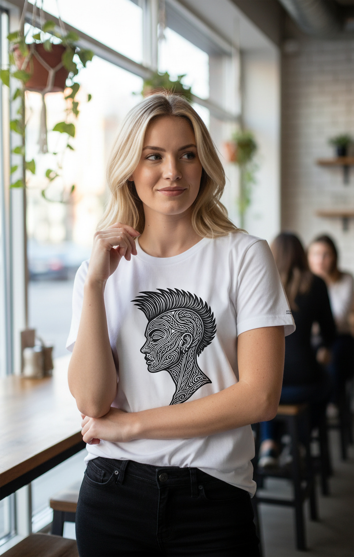 Model wearing a white t-shirt with a Studio VieKay black graphic design in a cafe setting