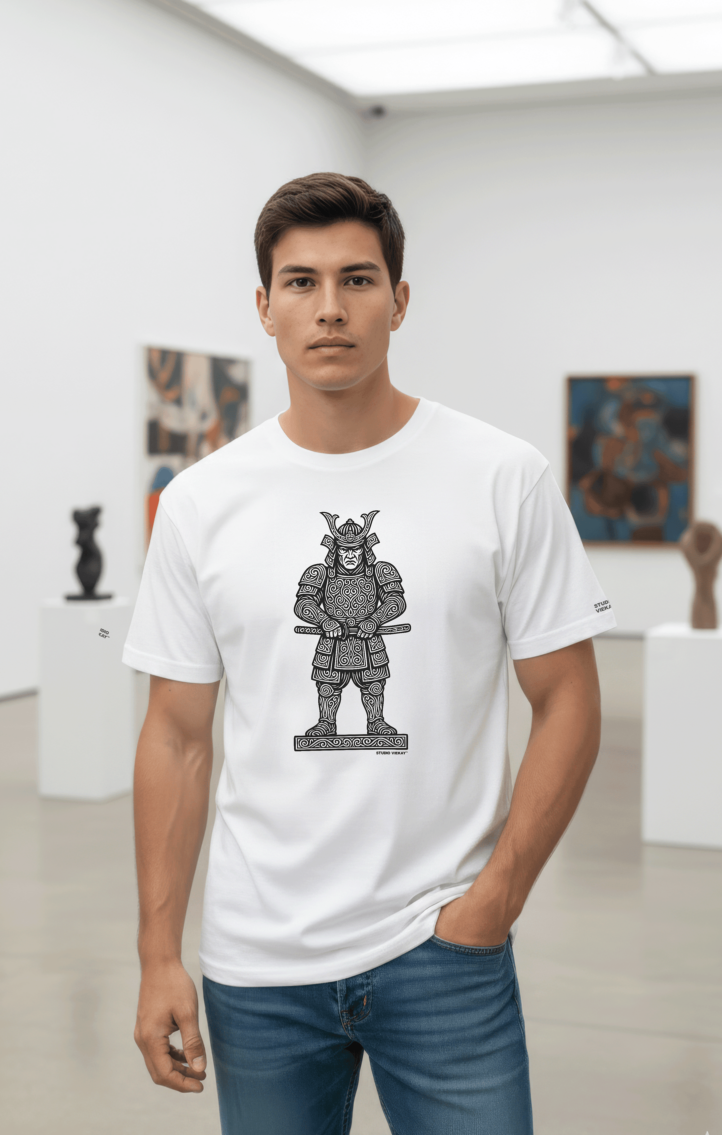 Model wearing a Studio Viekay white t-shirt with a Samurai graphic design in an art gallery.